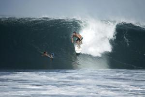 un hombre montando una ola en una tabla de surf en el océano en Casas Pelicano, en Playa Junquillal