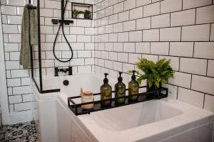a bathroom with a bath tub with bottles on a shelf at Paupies Place Seaside Stay in Cullercoats
