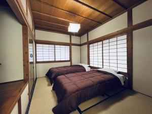 two beds in a room with two windows at Five Peaks Yudanaka in Yamanouchi