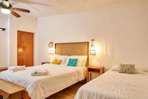 a bedroom with two beds and a ceiling fan at Aaki Hotel in Las Peñitas