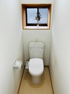 a small bathroom with a toilet and a window at Five Peaks Yudanaka in Yamanouchi