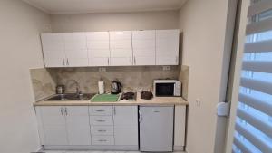 a kitchen with white cabinets and a sink and a microwave at Apartman Enjoy Arandjelovac in Arandjelovac