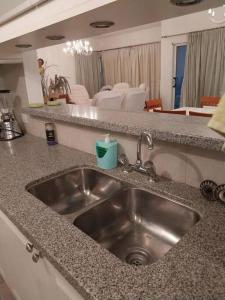um balcão de cozinha com um lavatório e uma sala de estar em Apartamento frente al Mar para 7 em Pinamar