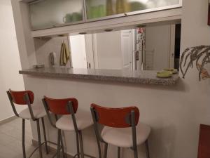 a kitchen with three bar stools in front of a counter at Apartamento frente al Mar para 7 in Pinamar