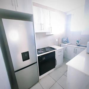a white kitchen with a stove and a refrigerator at NO: 75 WINDEMERE HOLIDAY FLAT in Durban
