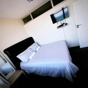 a bedroom with a white bed and a flat screen tv at NO: 75 WINDEMERE HOLIDAY FLAT in Durban