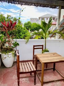 two chairs and a table on a balcony with plants at Balcony House in Zanzibar City