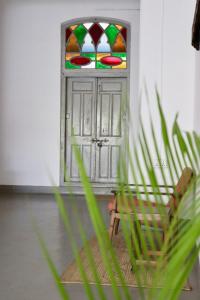 a chair in front of a door with a stained glass window at Balcony House in Zanzibar City
