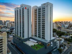 zwei hohe weiße Gebäude in einer Stadt bei Sonnenuntergang in der Unterkunft Aloft Santo Domingo Piantini in Santo Domingo