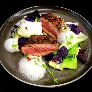 un plato de comida con carne y verduras. en moser-HOCHKÖNIG Genuss Wirtshaus Hotel, en Maria Alm am Steinernen Meer