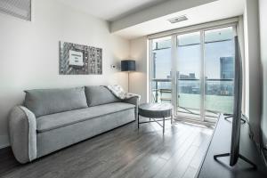 uma sala de estar com um sofá e uma grande janela em Luxury Condo w/Mesmerizing Sunset Views & FREE Parking em Toronto