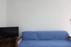 - un lit avec des draps bleus à côté d'une télévision dans l'établissement Suítes Praia dos Anjos - Arraial do Cabo, à Arraial do Cabo