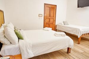 a bedroom with two beds with white sheets at Aaki Hotel in Las Peñitas