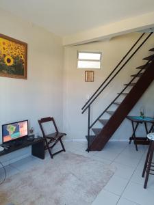 a living room with a staircase and a television at Duplex com dois Quartos in Salvador