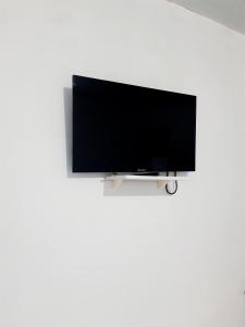 TV de pantalla plana colgada en una pared blanca en Pousada Aconchego Sol e Mar, en Maragogi