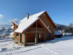 Cabaña de madera con techo cubierto de nieve en Guest House Velet, en Bukovel