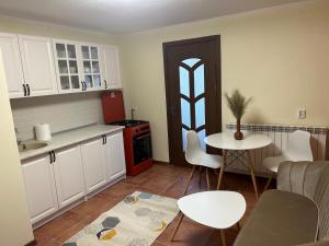 a kitchen with white cabinets and a table and chairs at Central langa Parc in Uricani