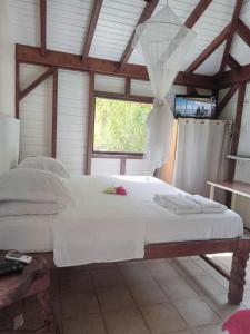 a bedroom with a large white bed with a window at GITE LOCA in Capesterre