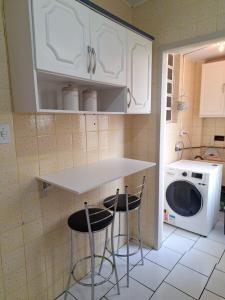 a kitchen with a counter and two stools and a washing machine at Charmoso apartamento próximo ao Consulado EUA in Porto Alegre