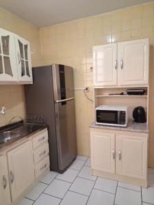 a kitchen with white cabinets and a stainless steel refrigerator at Charmoso apartamento próximo ao Consulado EUA in Porto Alegre