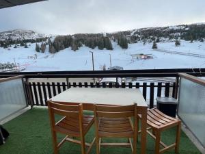 代沃呂伊的住宿－Moment magique aux pieds des pistes à Superdevoluy，一个带一张桌子和两把椅子的带滑雪场的阳台