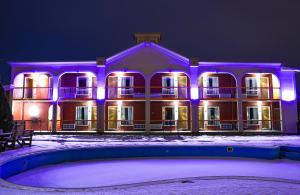 a large building with purple lights in the snow at Motel Classique in Joliette