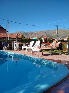 uma mulher deitada em cadeiras ao lado de uma piscina em Gracias Viejo em Merlo