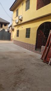 un parking vide devant un bâtiment jaune dans l'établissement Dave's abode, à Benin City
