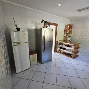 a kitchen with a refrigerator and a tile floor at Casa de campo em sítio de médio padrão com piscina aquecida e churrasqueira in Juquitiba