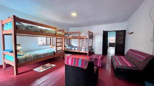 a room with three bunk beds and a couch at MORENAS BACKPACKERs in Cusco