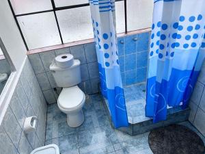 baño con aseo y cortina de ducha azul en MORENAS BACKPACKERs, en Cusco