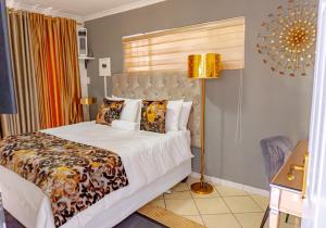 a bedroom with a large bed and a lamp at Homes of Ace Gold in Pretoria