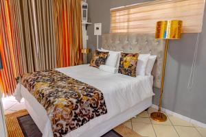 a bedroom with a large bed with a lamp at Homes of Ace Gold in Pretoria