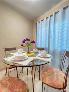 a dining room with a table with chairs and purple flowers at Casa en Ceiba 15 min de la playa in La Ceiba