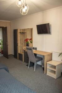 um quarto com uma secretária e uma televisão na parede em Готельно-ресторанний комплекс Фамілія em Bushtyno