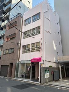 een hoog wit gebouw met een rode luifel bij Sakura Hotel Jimbocho in Tokyo