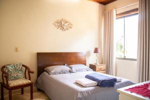 - une chambre avec un lit, une chaise et une fenêtre dans l'établissement Casa das Pedras, à Lagoa Santa