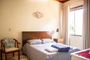 a bedroom with a bed and a chair and a window at Casa das Pedras in Lagoa Santa