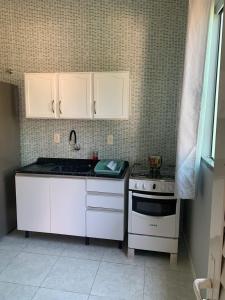 a small kitchen with white cabinets and a stove at Recanto dos Ganchos in Governador Celso Ramos