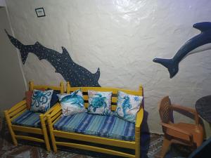 Kitnet no Farol Velho في سالينوبوليس: غرفة مع مقعد مع الوسائد ودلفين مرسوم على الحائط