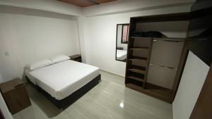 a small bedroom with a bed and a mirror at Apartamento Confort Quindío in Calarcá