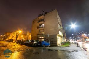 een gebouw met auto's geparkeerd op een parkeerplaats 's nachts bij Apartments Ivangrad in Berane