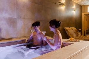 un hombre y una mujer sentados en una bañera con champán en Porta D'Oro Charming House II & Spa, en Alghero