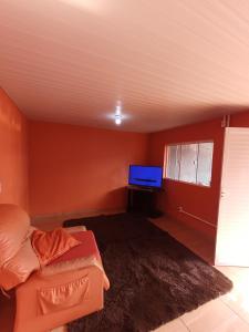 a living room with a couch and a flat screen tv at Casa inteira, Quarto p 3 pessoas com Ar, Sala Cozinha,Wifi,Garagem Coberta in Foz do Iguaçu