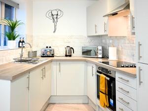 a white kitchen with white cabinets and appliances at Golden King Suite - Balcony & FREE Parking - Central Bedford in Bedford