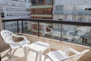 3 weiße Stühle und ein Tisch auf dem Balkon in der Unterkunft Cabello trendy in Buenos Aires