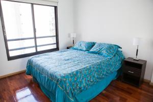 ein Schlafzimmer mit einem Bett mit blauer Decke und einem Fenster in der Unterkunft Cabello trendy in Buenos Aires