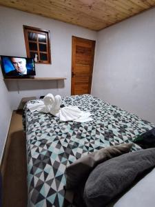 a bedroom with a bed with a tv on the wall at Pousada Lofts e Suítes Campos in Campos do Jordão