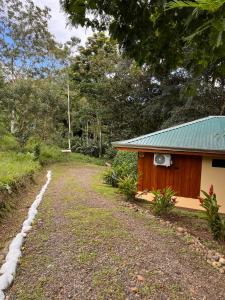a house with a green roof next to a dirt road at Gambas Lodge in Fortuna