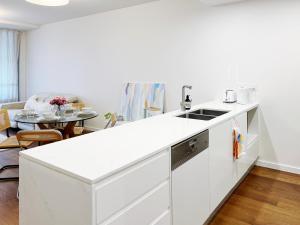 a white kitchen with a sink and a table at Mascot Cozy Apartment + Free Parking in Sydney